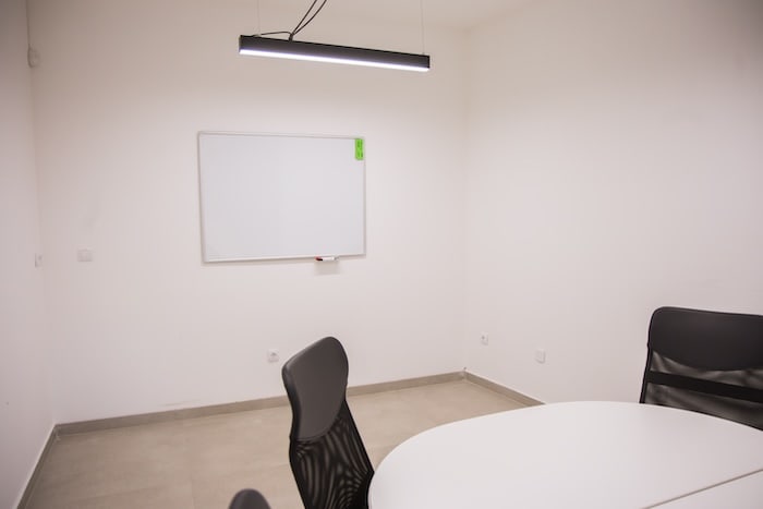 Glass-walled meeting room with conference table and presentation screen