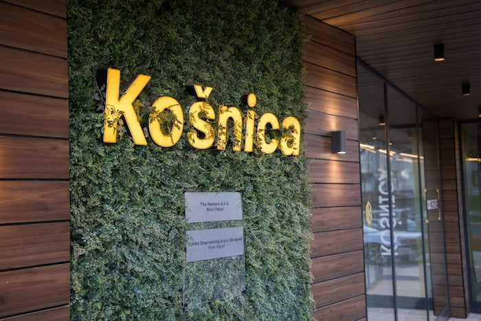 Exterior entrance to Košnica Beehive with yellow signage on living wall